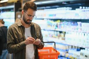 Handsome young man choosing food in the supermarket. photo