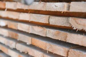 Stack of lumber of a wooden board from a tree, close-up, background. Wooden boards at the sawmill, carpentry workshop. Sawing and air drying of wood. Woodworking industry. Wooden boards photo