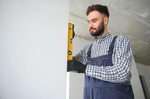 builder posing with spirit level at construction site photo