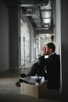 triste despedido empresario sentado fuera de reunión habitación después siendo despedido. foto