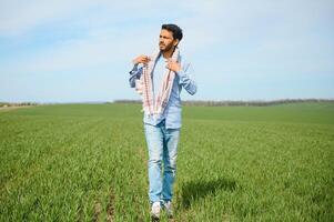 Portrait of farmer standing in a wheat field. farmer stands in green wheat field, looks, examines his crop photo