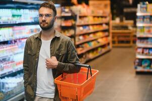 Handsome young man choosing food in the supermarket. photo