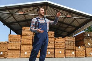 Carpenter in uniform check boards on sawmill photo