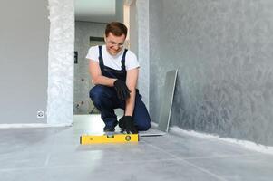 industrial worker, handyman installing big ceramic tiles photo