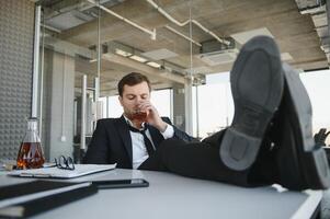 Businessman drinking from stress at workplace photo