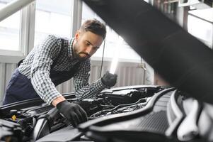 adulto hombre en azul de colores uniforme trabajos en el automóvil salón. foto