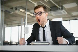 Angry businessman sitting at his desk and screaming at his employees. photo