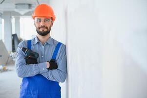 Portrait of young and hardworking constructor posing in big unfinished room. Building concept photo