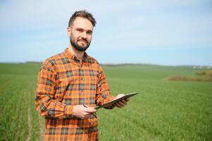 A young farmer inspects the quality of wheat sprouts in the field. The concept of agriculture. photo