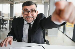 Angry businessman sitting at the table and screaming over. photo