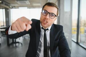 enojado empresario sentado a el mesa y gritando. foto