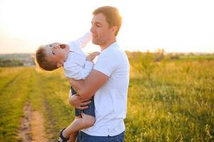 del padre día. contento familia padre y niñito hijo jugando y riendo en naturaleza a puesta de sol foto