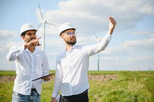 Young maintenance engineer team working in wind turbine farm. photo