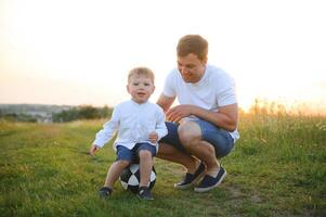 del padre día. contento familia padre y niñito hijo jugando y riendo en naturaleza a puesta de sol foto