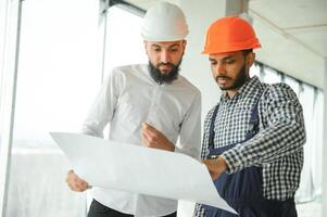 Young attractive arabic industrial engineer in hard hat. Professional and industry, builder architect job, worker checking work at plant indoor photo