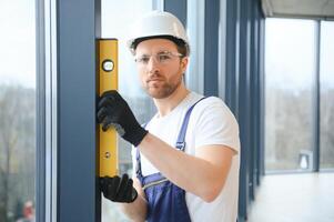 handsome young man installing bay window in new house construction site. photo