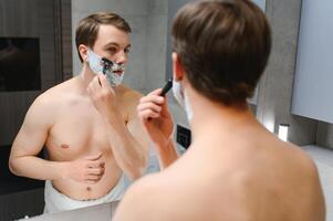 Serious guy shaving his beard photo