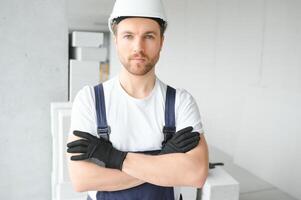Portrait of a young foreman in uniform standing on a construction site indoors near a stepladder. photo