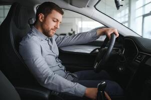 Happy young driver behind the wheel inside new car. Lifestyle scene in the car dealership photo