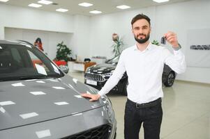 Sí, eso es mi nuevo coche. cliente en coche concesión. joven hombre con llaves en mano foto