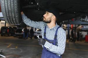 retrato de un mecánico reparando un levantado coche foto