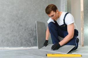 A male construction worker installs a large ceramic tile photo