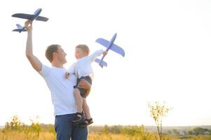 Cute little boy and his handsome young dad are smiling while playing with a toy airplane in the park. photo