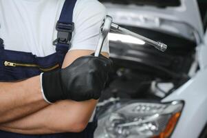 con herramienta en mano. adulto hombre en de colores uniforme trabajos en el automóvil salón foto