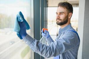 Male professional cleaning service worker in overalls cleans the windows and shop windows of a store with special equipment photo