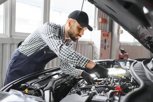 Examen mecánico debajo del capó del automóvil en el garaje de reparación foto