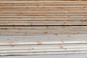 Stack of lumber of a wooden board from a tree, close-up, background. Wooden boards at the sawmill, carpentry workshop. Sawing and air drying of wood. Woodworking industry. Wooden boards photo