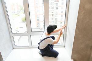 Man putting filling between window and wall in a new house photo