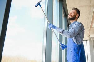 Male janitor cleaning window in office photo