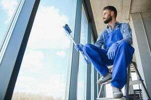 Young man cleaning window in office photo