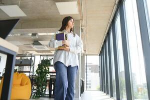 Schoolgirl standing with books and backpack at school. photo