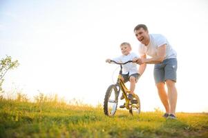 padre ayuda su hijo paseo un bicicleta foto