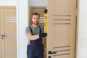 hermoso joven hombre instalando un puerta en un nuevo casa construcción sitio. foto