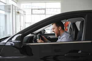 joven hombre es elegir un nuevo vehículo en coche concesión. foto