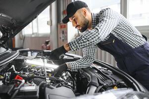 Examen mecánico debajo del capó del automóvil en el garaje de reparación foto