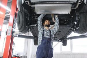 adulto hombre en azul de colores uniforme trabajos en el automóvil salón. foto