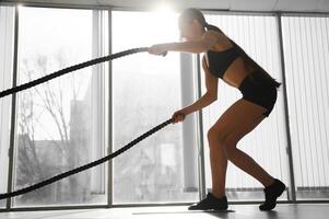 Woman training with battle ropes in gym photo