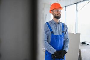 Portrait of young and hardworking constructor posing in big unfinished room. Building concept photo