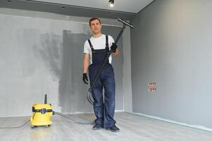 un trabajador aspiradoras un habitación después reparando el pisos Departamento después renovación con un vacío limpiador. foto