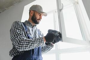 Worker in installing white plastic upvc window on house. photo