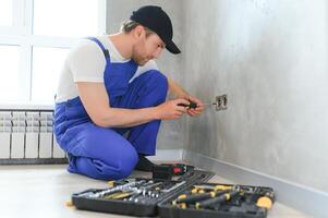 profesional electricista trabajando en un hogar eléctrico sistema, él es instalando un pared enchufe foto