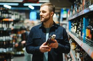 un hombre toma alcohólico bebidas desde el supermercado estante. compras para alcohol en el almacenar. foto