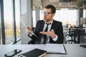 enojado empresario sentado a su escritorio y gritando a su empleados. foto