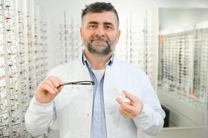 Eye doctor choosing between eyeglasses and lenses standing in front of the eye chart in the cabinet photo