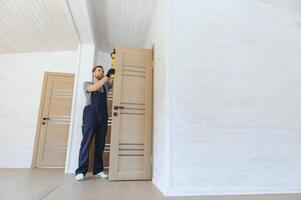un hermoso masculino trabajador es instalando un nuevo puerta en un casa. foto