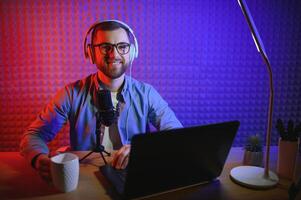 Young man recording or streaming podcast using microphone at his small broadcast studio. Content creator. photo